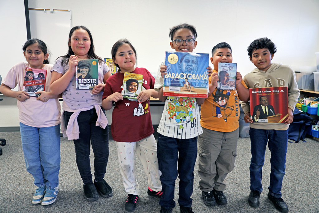 Six students hold up books