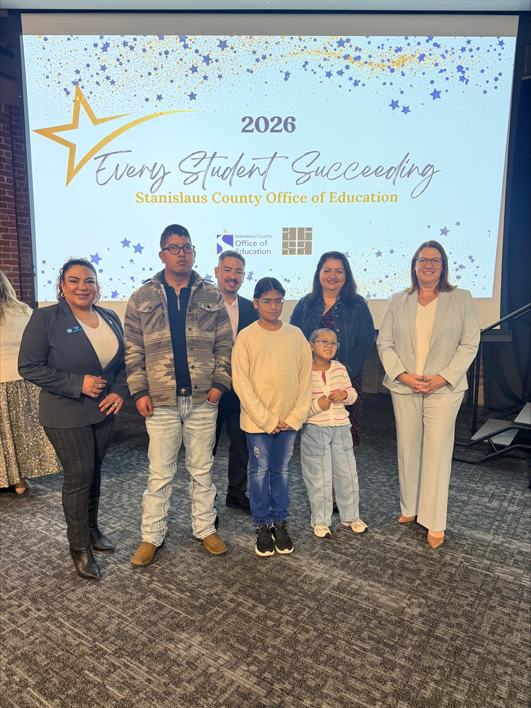 Students with Superintendent and three Board members in front of Every Student Succeeding backdrop