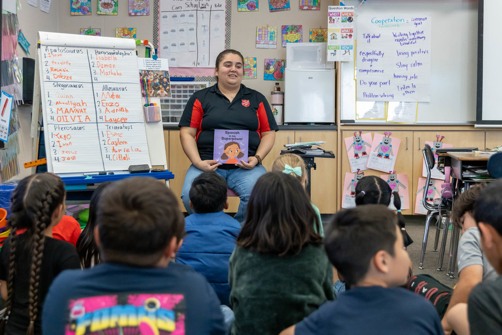 A woman reading a book to a classroom full of students