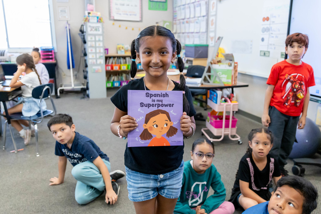 A student holding a book and smiling