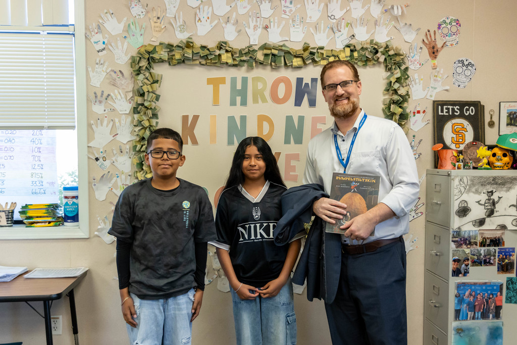 A man and two students smiling for the camera