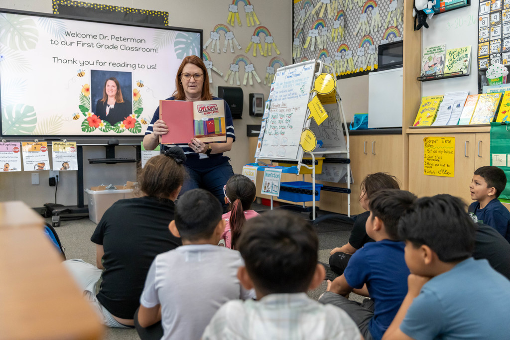 A woman reading a book to a classroom full of students