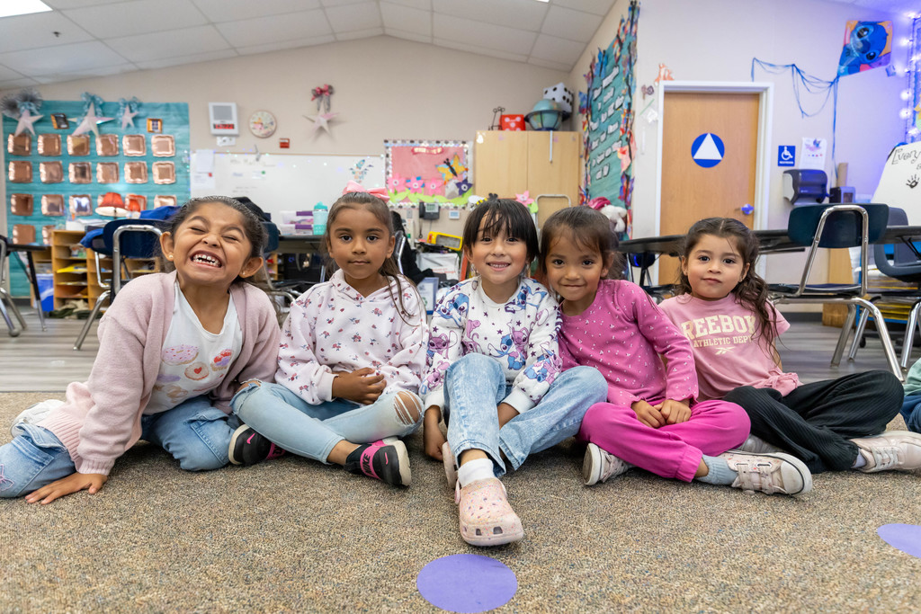 Group of students smiling while sitting on the floor