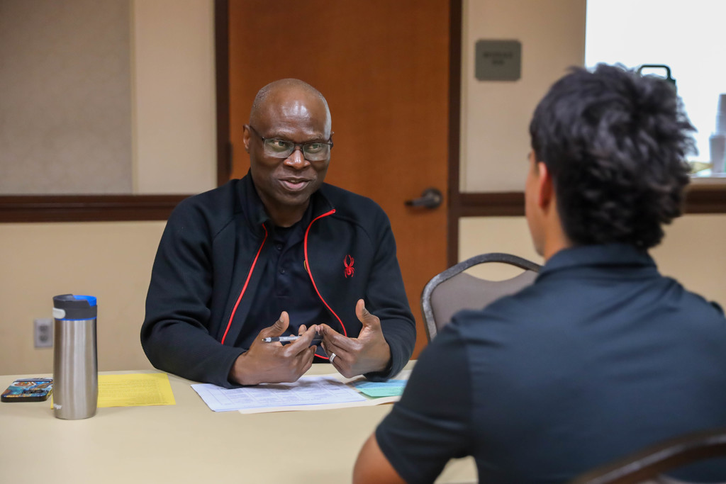 Adult interviewing students at a table