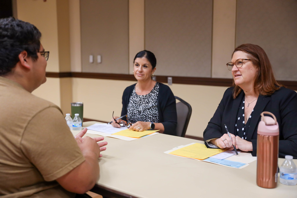 Adults interviewing students at a table