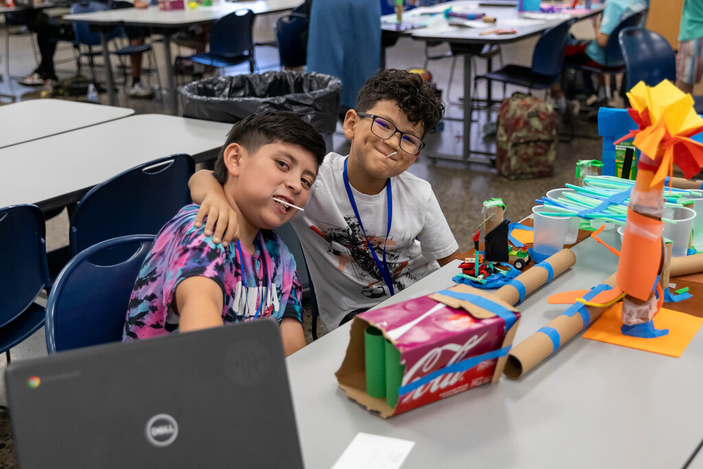 two students smiling while working on a project