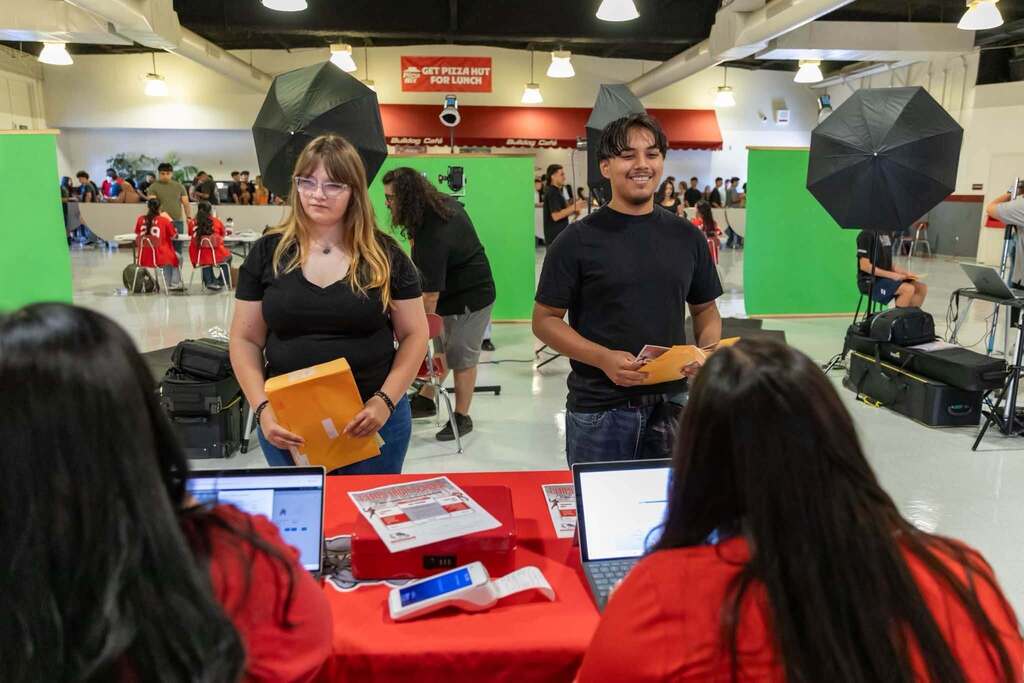 Two CHS students picking up packets at table