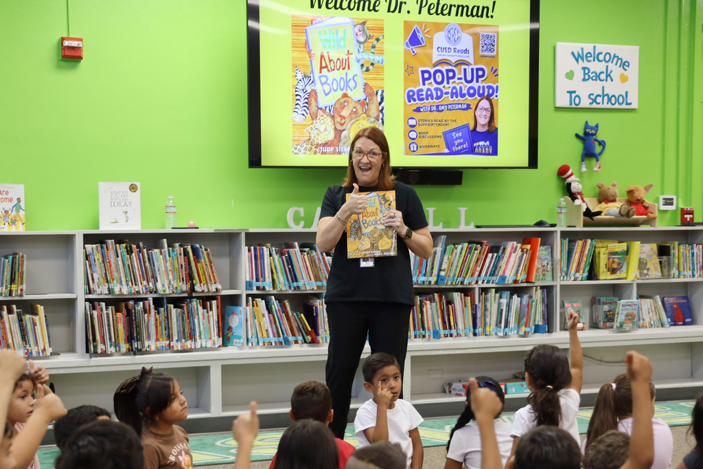 Dr. Peterman holding a book and giving thumbs up