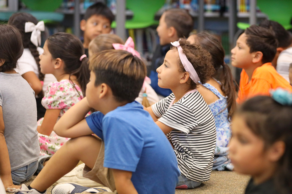 Young students sitting on the floor listening to a story being read