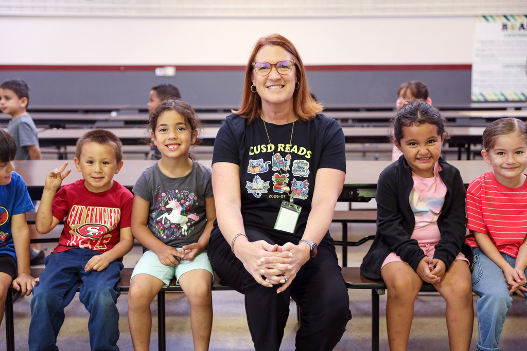 Dr. Peterman sitting on a bench with four kindergartners