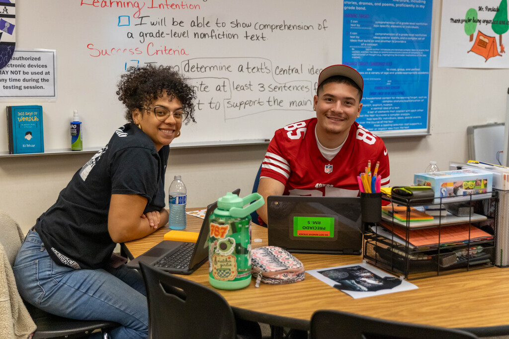 staff and student smiling at a table