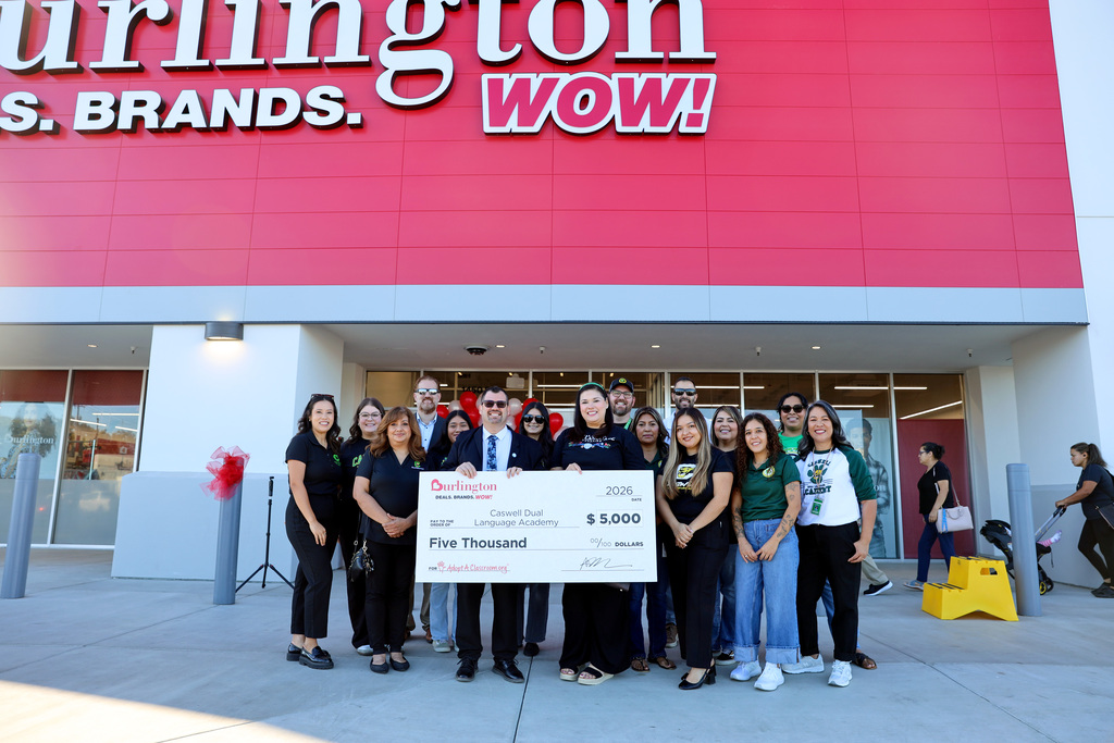 Caswell Principal and staff, along with Burlington store manager, hold giant check in front of new Hatch Road store