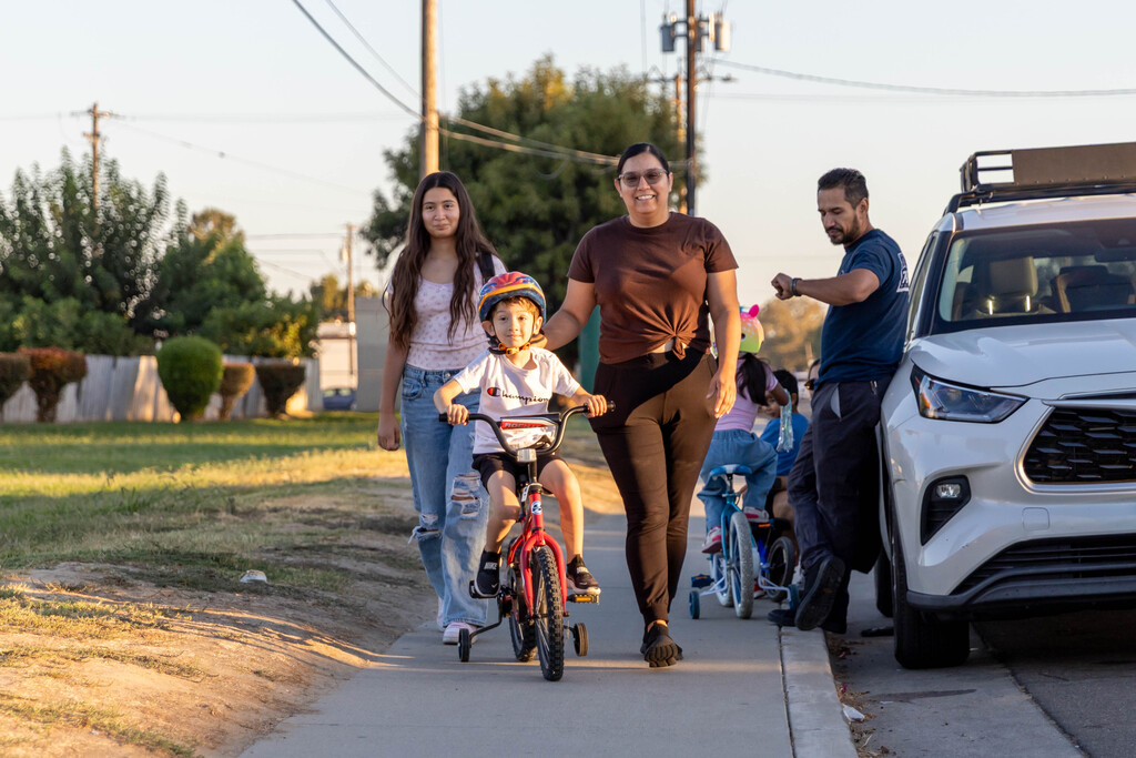 a family walking to school with one riding a bike
