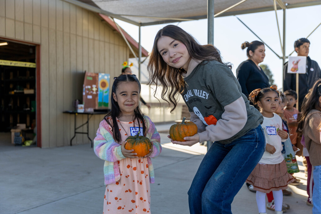 two students holding pumpkins