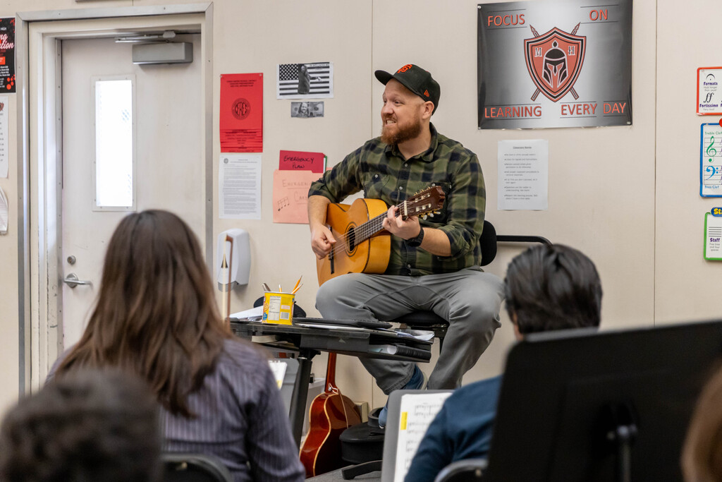 Teacher playing guitar in front of class