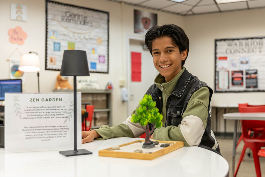 Smiling student seated at desk with Zen garden