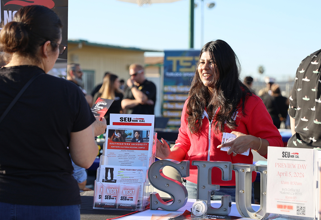 College representative interacts with community member at info table