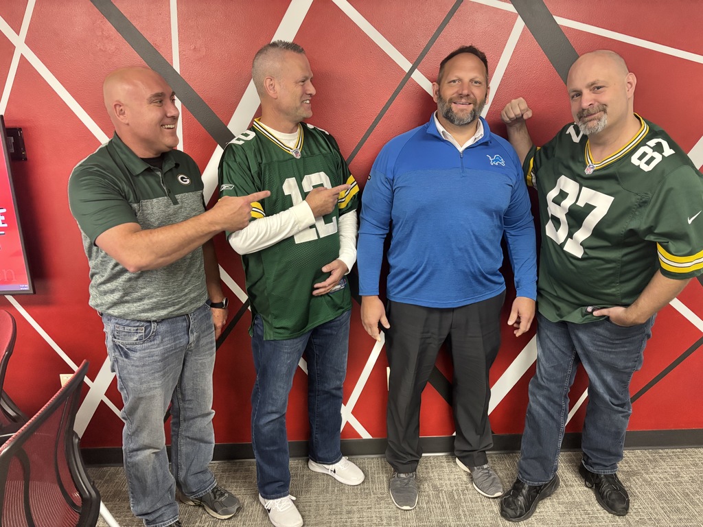 Superintendents posing for a picture in their favorite teams shirts.