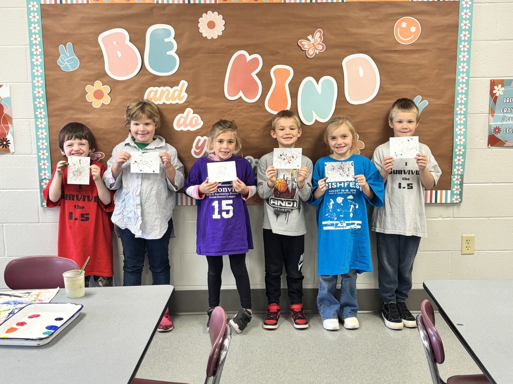 Elementary students hold up their art.