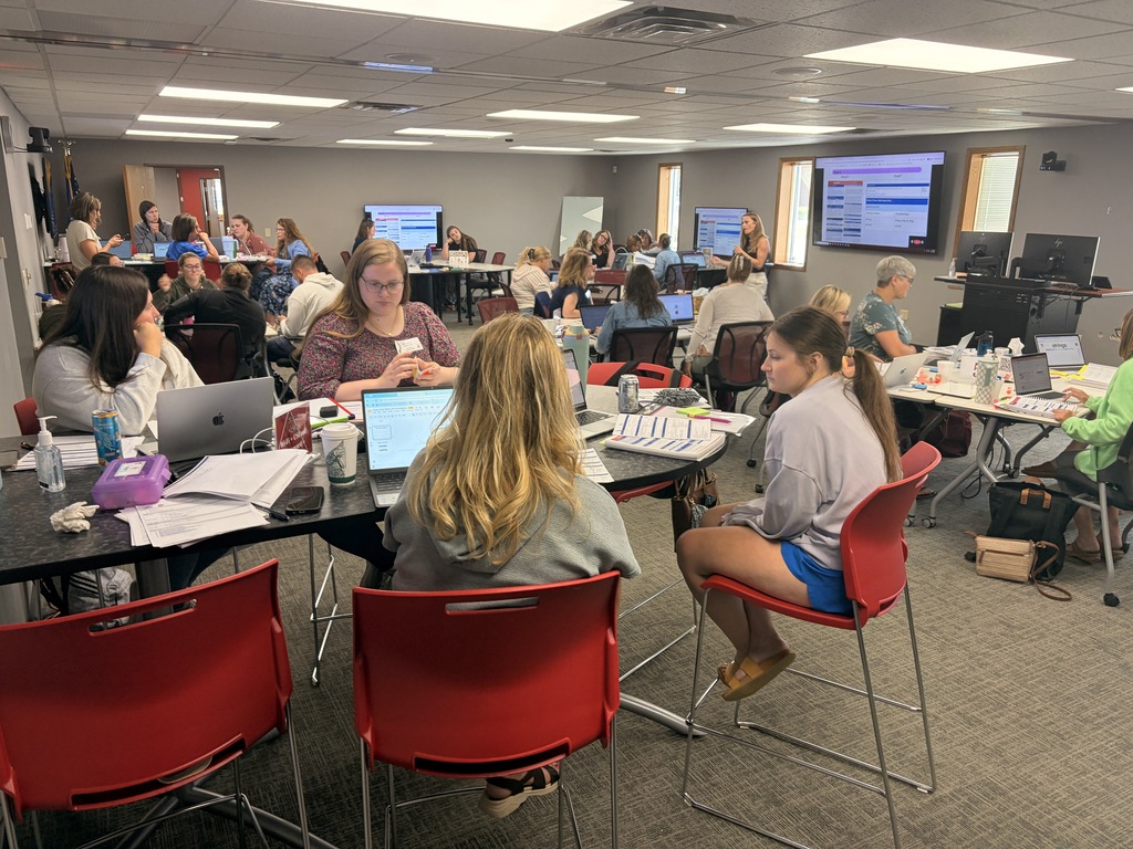 A large group work session at individual tables.