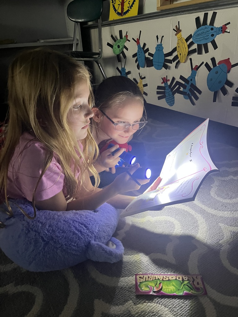 Students reading books using flashlights.