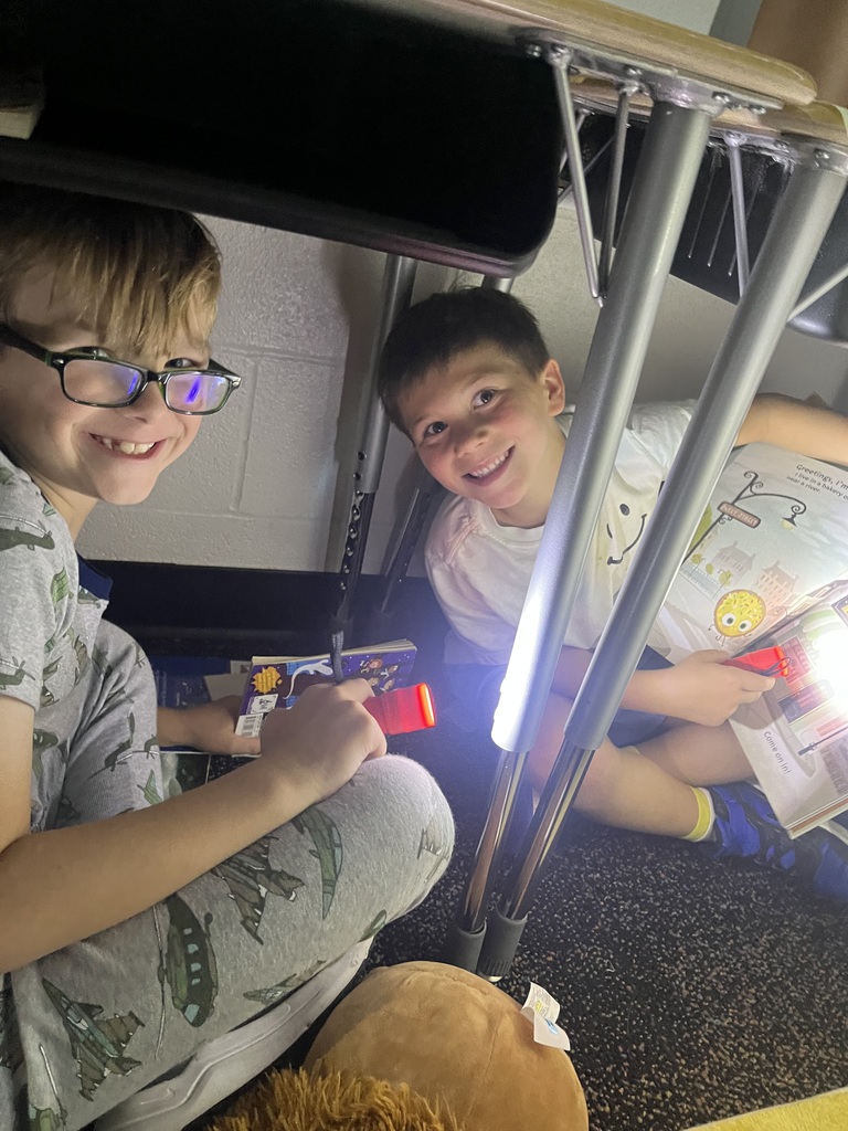 Students reading books using flashlights.