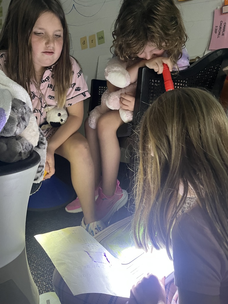 Students reading books using flashlights.
