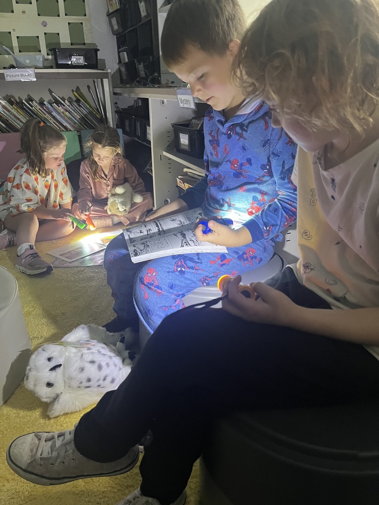 Students reading books using flashlights.