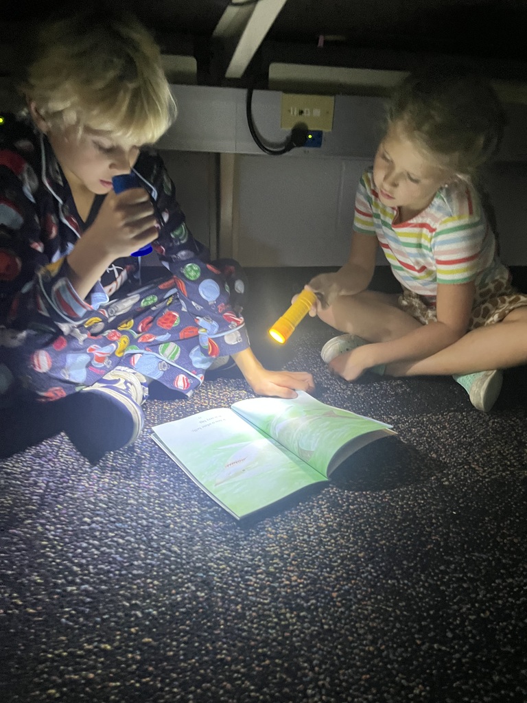 Students reading books using flashlights.