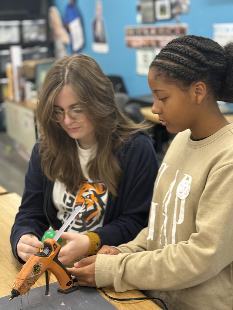 Using hot glue, students experimented with items like beads, hardware, popsicle sticks, and balloons to adjust balance and achieve neutral buoyancy.