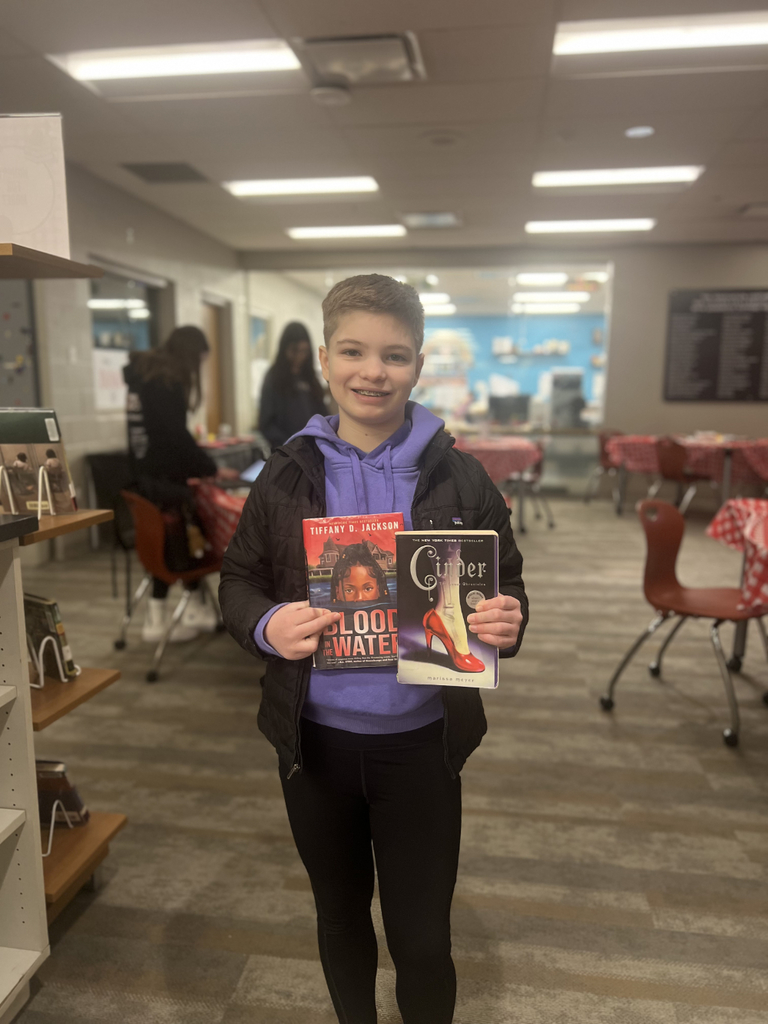 Middle school students sit at decorated tables in the Innovation Center, transformed into the IC Cafe, sampling books, taking notes, and enjoying drinks while exploring a variety of high interest titles.
