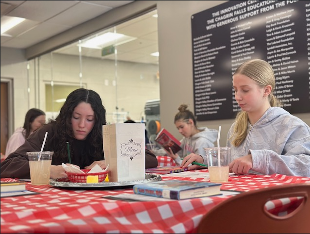 Middle school students sit at decorated tables in the Innovation Center, transformed into the IC Cafe, sampling books, taking notes, and enjoying drinks while exploring a variety of high interest titles.