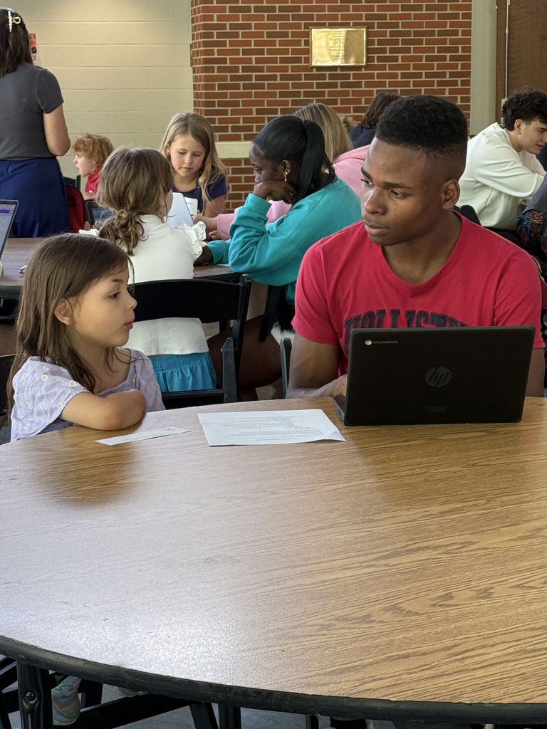 2nd grade students working with HS students to create poster for their mini-society projects.