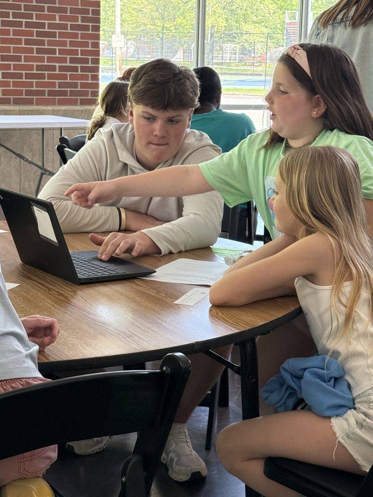 2nd grade students working with HS students to create poster for their mini-society projects.