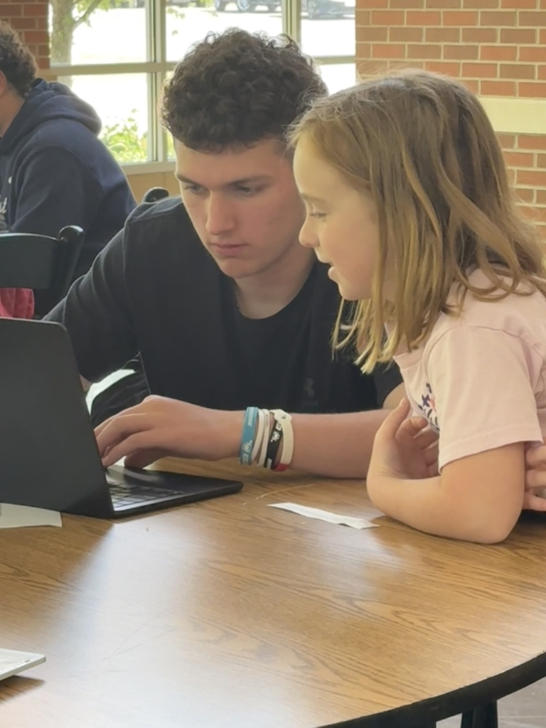 2nd grade students working with HS students to create poster for their mini-society projects.