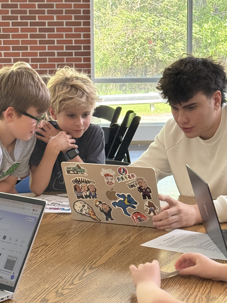 2nd grade students working with HS students to create poster for their mini-society projects.