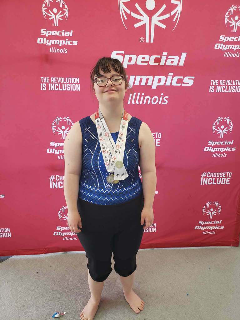 Person with eyeglasses stands barefoot before a red backdrop with Special Olympics text and logo.