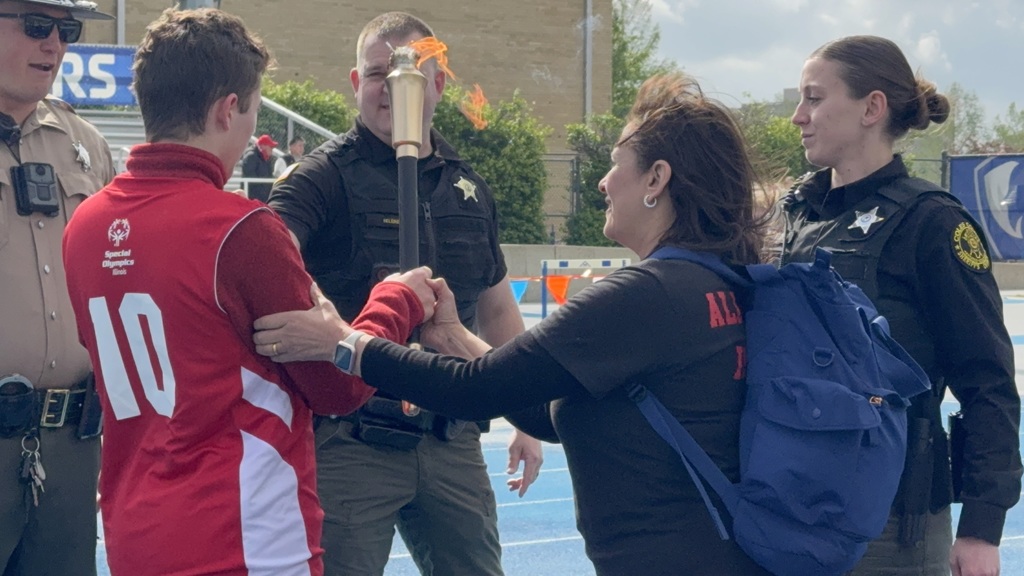 Several people standing on a track field, a person in a red jersey with number 10 being congratulated.