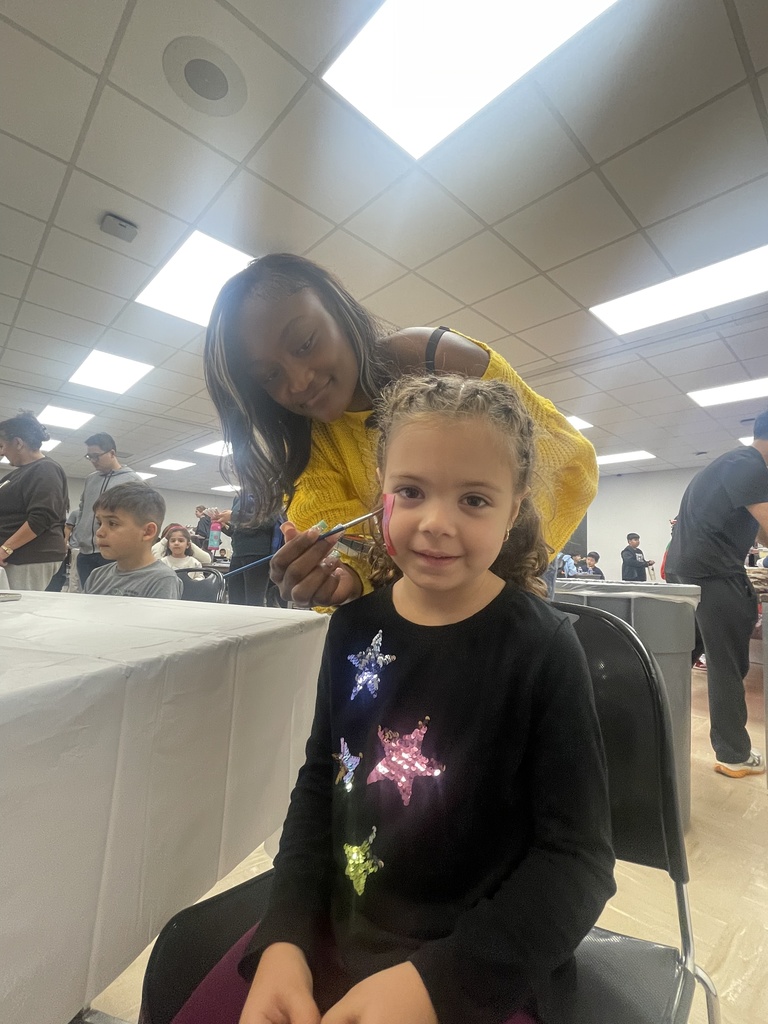 A young girl is getting her hair cut by a woman in a room with bright lighting.