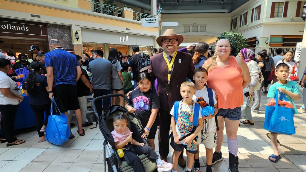 A group of people stand in a mall, including Superintendent Geovanny Ponce, with children and adults.