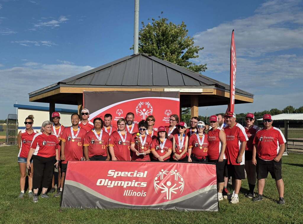 A team of people in red shirts poses for a photo in front of a sign and banner.