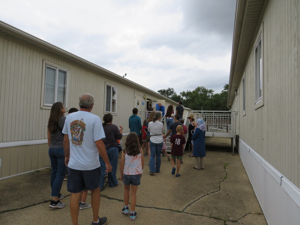 A group of people, some in sneakers, walking by modular housing on a cloudy day.