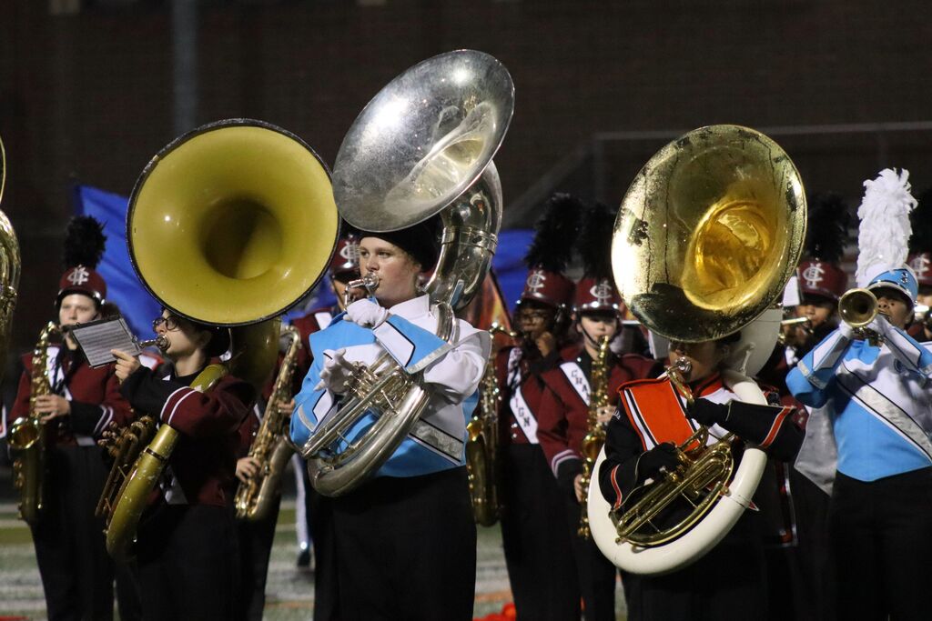 Students from Champaign Central High School, Champaign Centennial High School and Urbana High School marching bands are playing together with brass instruments.