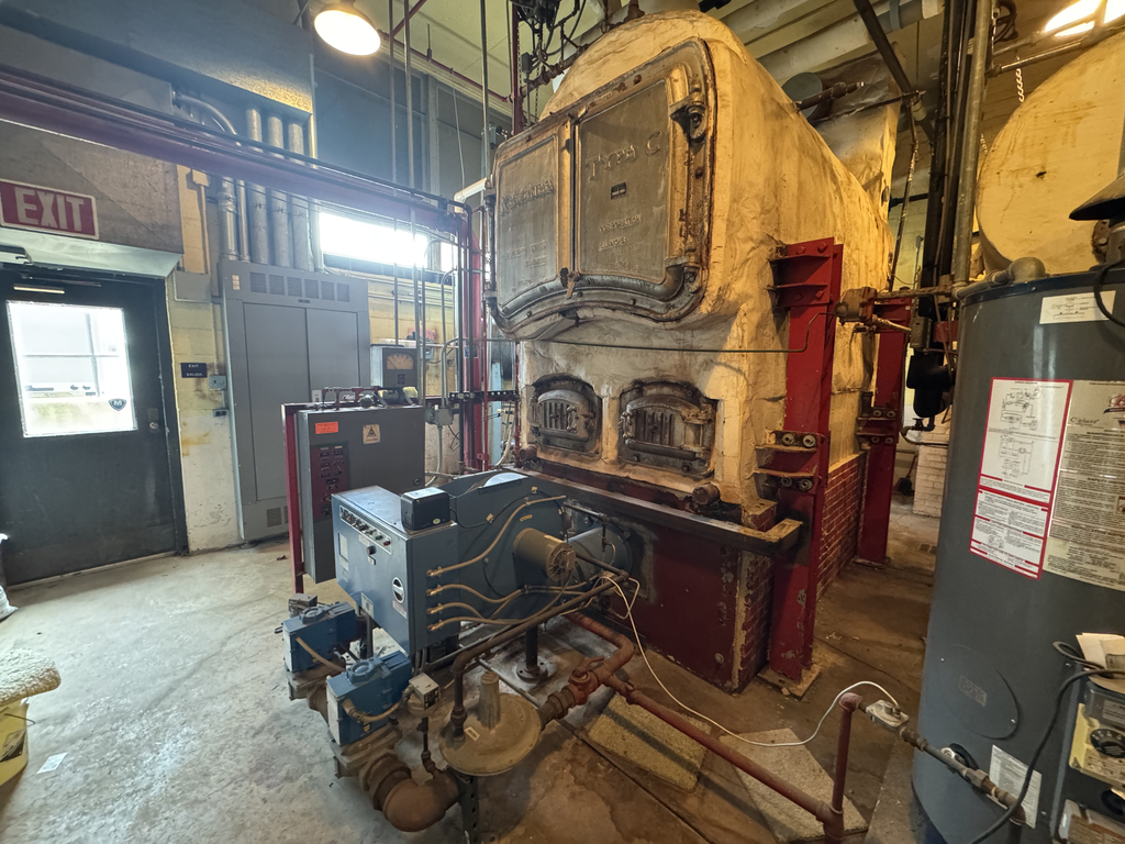 Industrial facility with metal machinery and equipment, including a boiler and large tanks. Bright lighting.