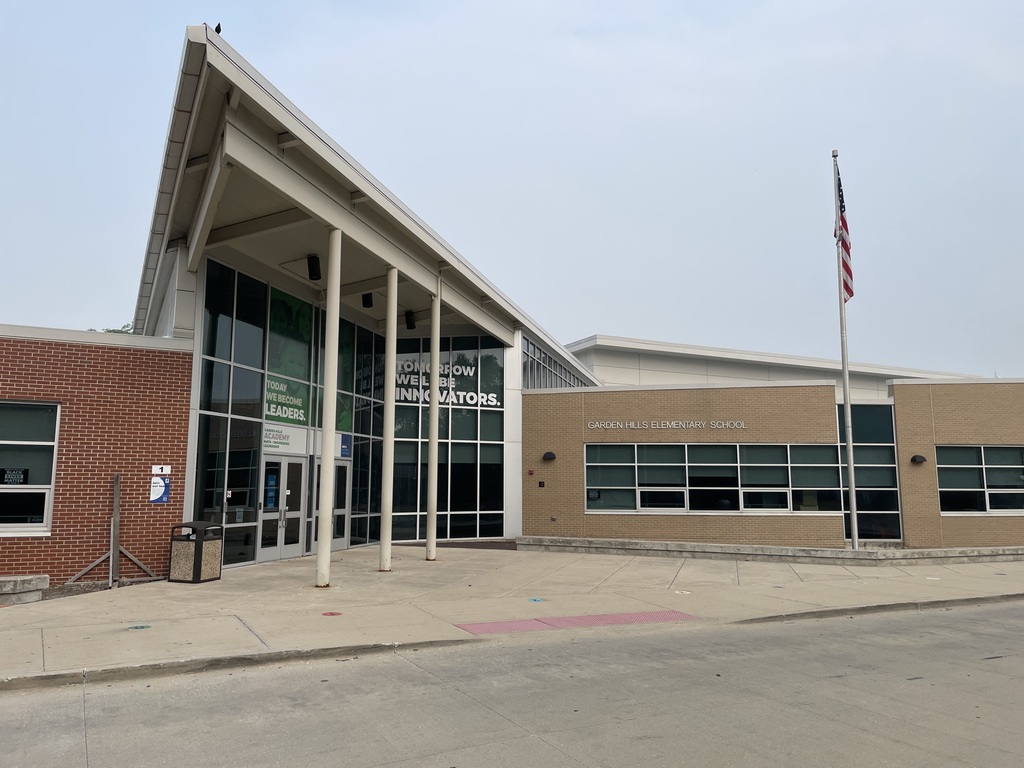 Building with an angled roof, large windows, and a flag on a pole in front.