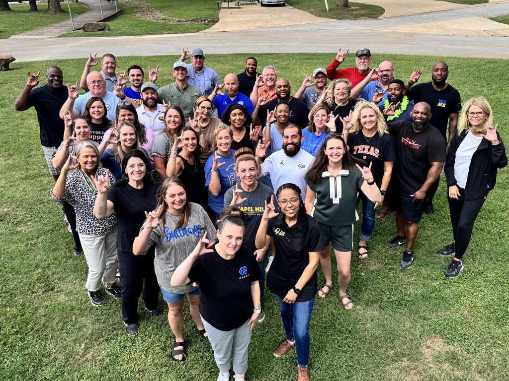 a group of staff gather for a photo throwing up the Chapel Hill hand sign