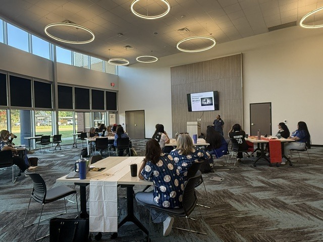 a large room with people in it listening to a presentation