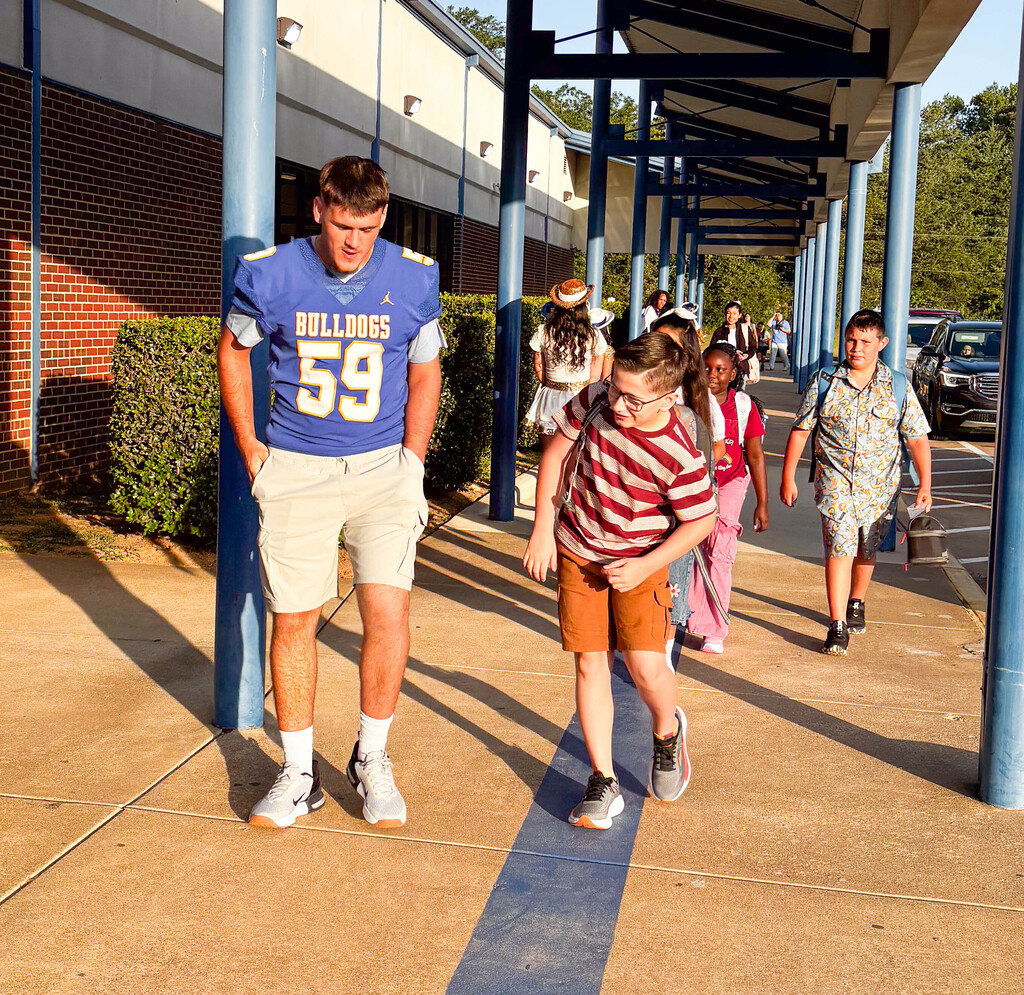 a football player walking a student into class