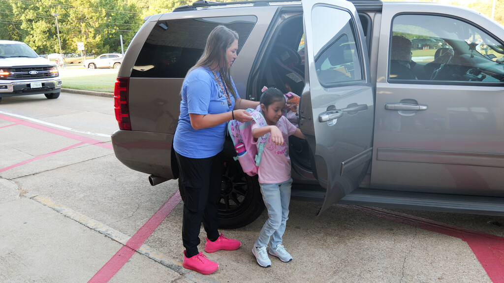 a teacher helping a student get out of the car