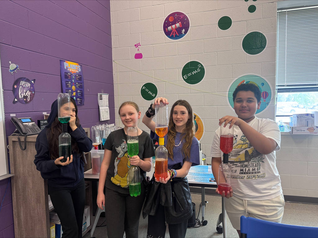 four students with jars full of colored liquid at the science center